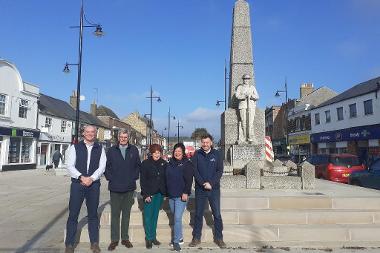 Officers, members and project partners beside war memorial